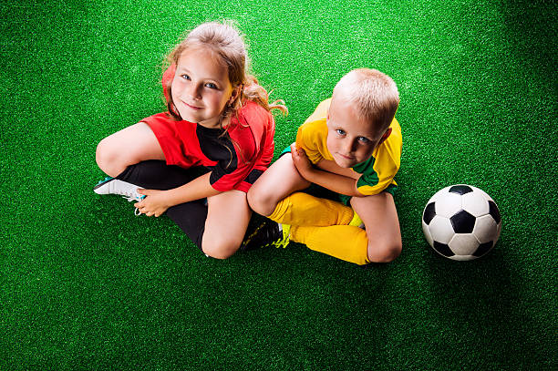 zwei nicht erkennbare kleine fußballer gegen grünes gras - soccer child indoors little boys stock-fotos und bilder