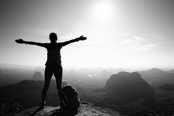 silhouette of cheering woman hiker open arms at mountain peak silhouette of cheering woman hiker open arms at mountain peak courage photos stock pictures, royalty-free photos & images