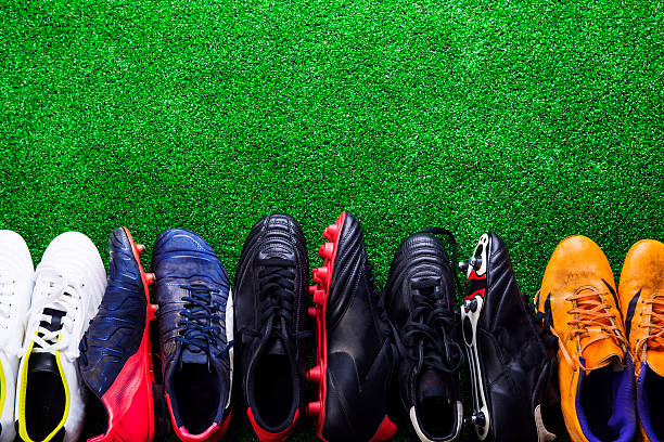 Various cleats against green artificial turf, studio shot Various colorful cleats against artificial turf, studio shot on green background. Flat lay, copy space. cleats stock pictures, royalty-free photos & images