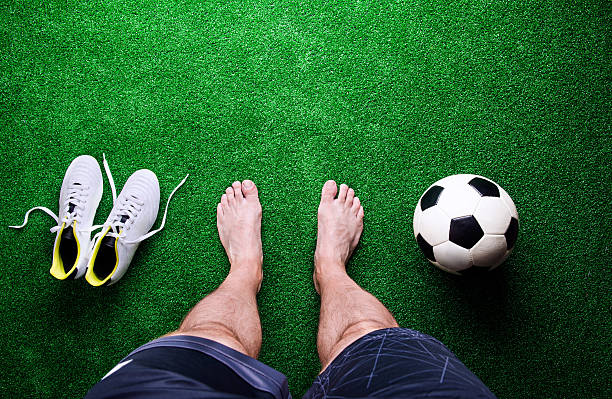 istock Barefoot football player against green grass, studio shot 542311160
