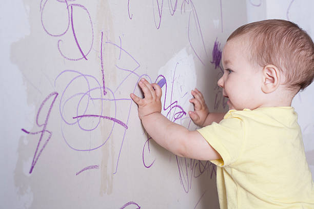 istock Baby boy drawing with wax crayon on plasterboard wall 542312444
