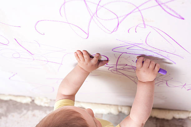 istock Baby boy drawing with wax crayon on plasterboard wall 542312468