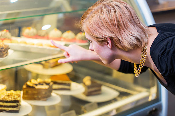 istock Cute young girl looking at display window with cakes 542312964