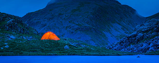 istock Camping tent illuminated against blue dusk mountains panorama Lake District 542315798