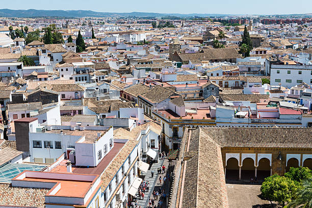 Cordoba, Spain - May 20, 2015: Aerial view of the tiled rooftops and Patio de los Naranjos outside the Mosque-Cathedral in Córdoba, with the street Cardenal Herrero full of tourists and locals.
