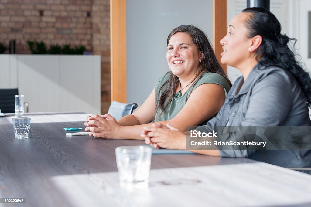 Two Maori women in business meeting Two Maori women on one side of table in involved in discussion during business meeting Māori People Stock Photo