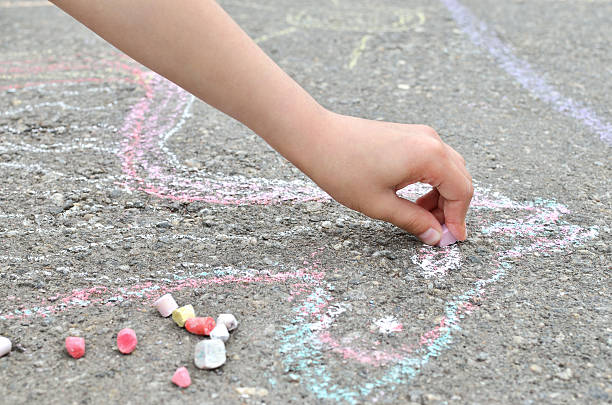 istock Children's hand draws with chalk on the pavement. Creative leisure. 542328112