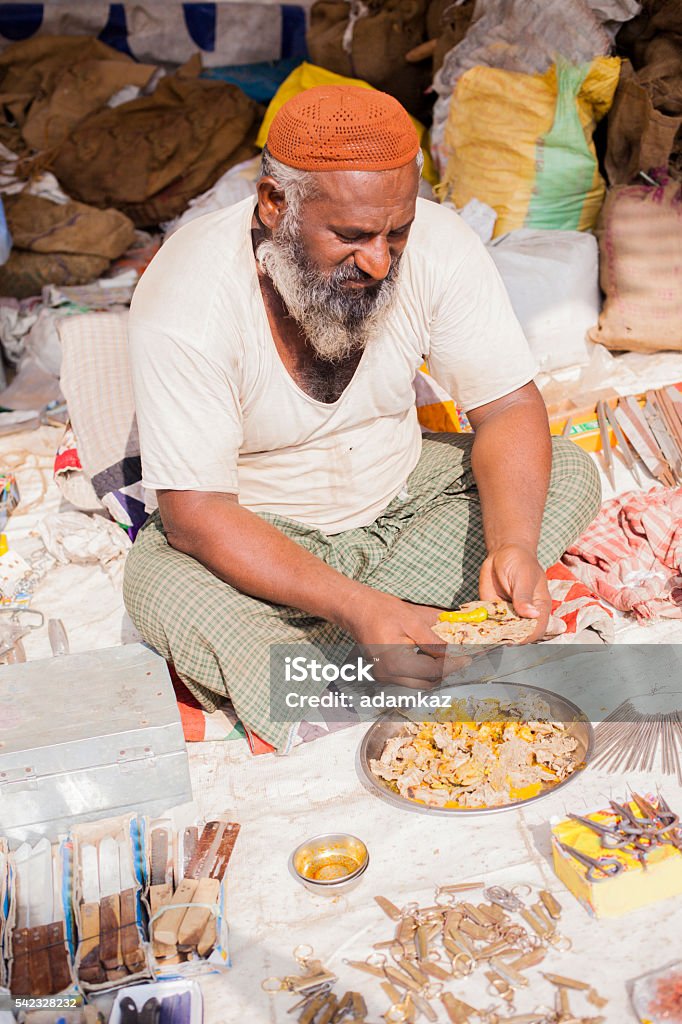 Adult Senior Indian Vendor On Lunch Break Portrait of an Indian vendor on lunch break at Pushkar Camel Fair Eating Stock Photo