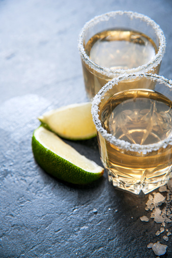 Tequila shot with lime and sea salt on black stone table