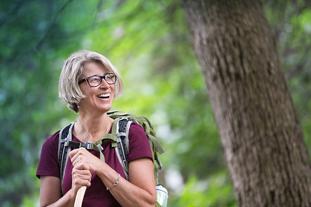 donna anziana felice con zaini - hiking senior adult exercising outdoors foto e immagini stock