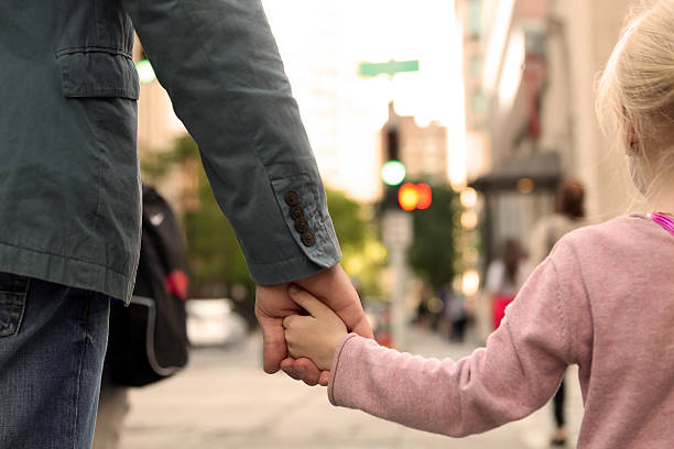 father holding  the daughter/ child  hand  behind  the traffic lights father holding  the daughter/ child  hand  behind  the traffic lights way to school stock pictures, royalty-free photos & images