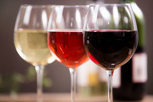 Wine tasting event. Red, white, and rose wine selections on outdoor patio table.  Wine bottles background. Rustic wooden table.  No people.