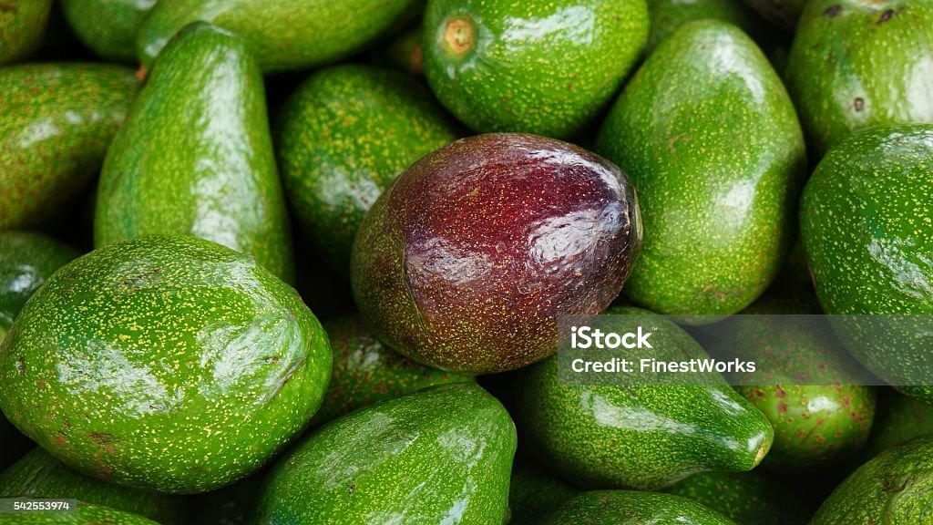 Ripe red avocado in bunch of green Avocados Ripe red avocado in bunch of green avocados. Stack of delicious fruits. Avocado Stock Photo