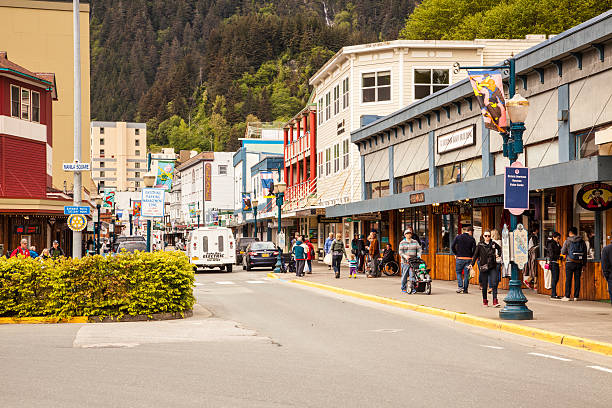 Store Fronts in Downtown Juneau, Alaska Juneau, Ak, USA, May 10, 2016.  Shoppers walk along South Franklin Street in downtown Juneau Alaska. Juneau is Alaska's capital city.  Cruise ships dock at a pier very close to this location and supply the city with a high percentage of its tourists. juneau stock pictures, royalty-free photos & images
