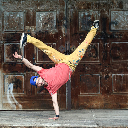 Male Hip-hop dancer breakdancing, standing on one hand. About 25 years old Caucasian man.