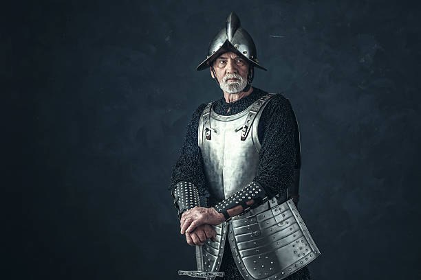 istock Knight in armor with gray beard holding sword. 542564514