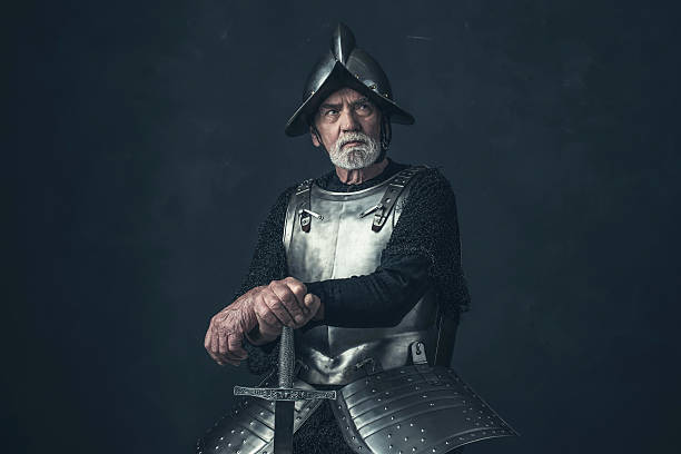 Knight with beard in armor leaning on sword. Knight with beard in armor leaning on sword. knight person photos stock pictures, royalty-free photos & images