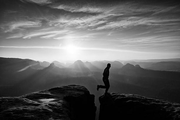 istock Happy man  jumping between rocks, misty mountains. 542571140