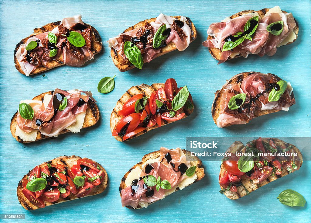 Brushetta snacks for wine. Variety of small sandwiches on turquoise Brushetta snacks for wine. Variety of small sandwiches on turquoise blue backdrop, top view Baguette Stock Photo