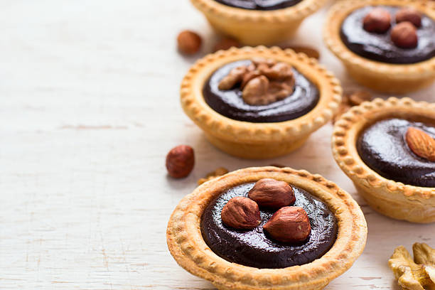 istock Nutty chocolate dessert small tarts on a white background, space 542581832