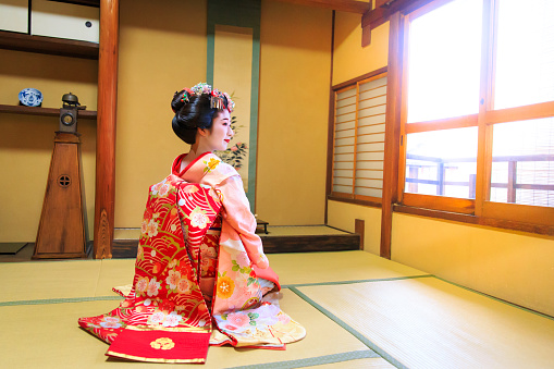 Young Maiko girl sitting in Japanese tatami room with smile