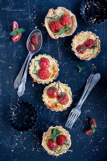 home made tarteletts with cherry tomatoes on black stock photo