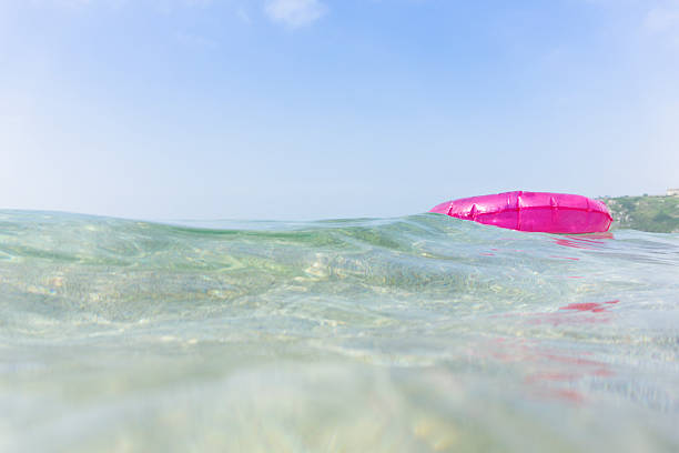 istock Pink rubber ring floating in the sea, South Cornwall. 542588408