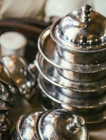 In an Indian restaurant, close-up shot of dishes such as cups, saucers, salt and pepper shakers and small stainless steel serving dish.