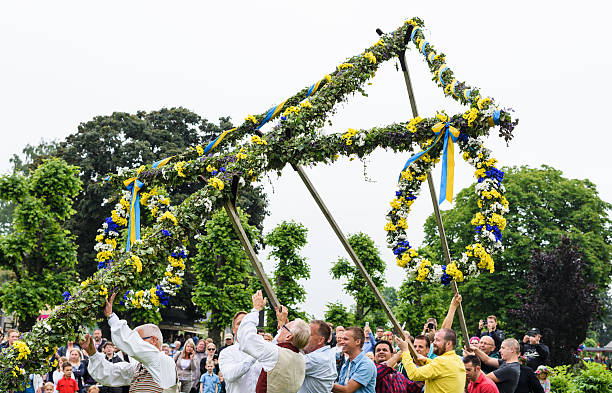 Raising the maypole at midsummer Stockholm, Sweden - June 24, 2016: A group of male volunteers working on raising the maypole in a traditional manner at a midsummer celebration in Hågelbyparken, botkyrka.  summer solstice stock pictures, royalty-free photos & images