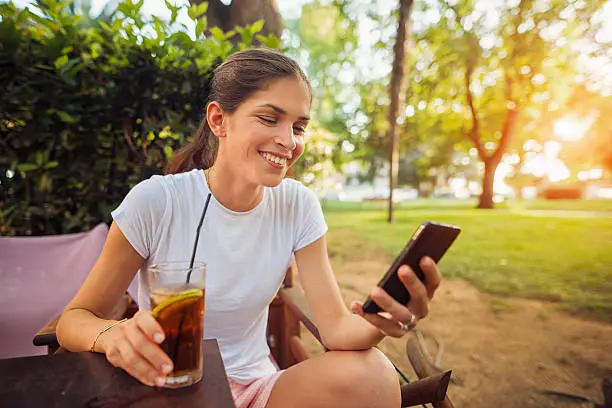 Photo of Woman with a phone and ice tea in the restaurant