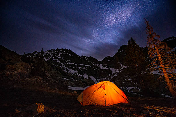 Glowing Tent Backpacking Under the Stars at Night Glowing Tent Backpacking Under the Stars at Night - Scenic alpine basin at high elevation in summer. Tent glowing under the night sky full of stars. space milky way star night stock pictures, royalty-free photos & images