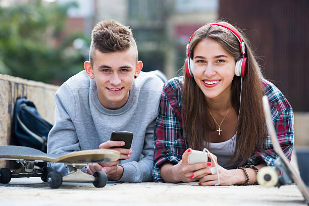 adolescente y su novia con los smartphones - video game friendship teenager togetherness fotografías e imágenes de stock