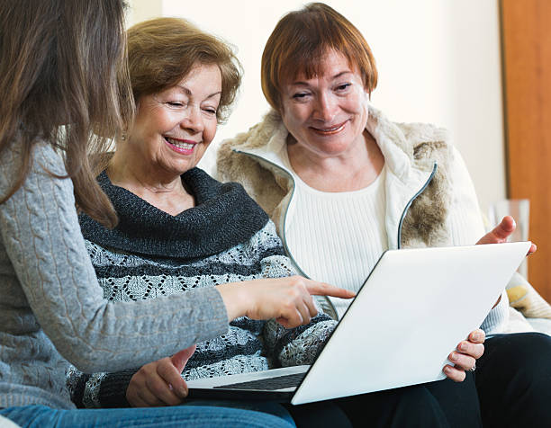 istock Cute girl teaching smiling senior women using laptop 542694918