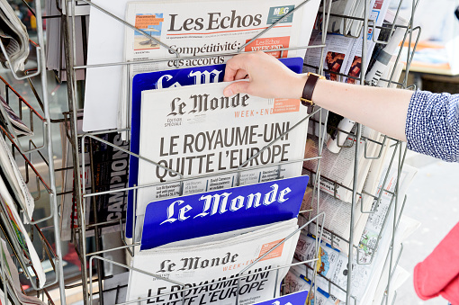 Strasbourg, France - June 25, 2016: Woman buying Le Monde newspaper with shocking headline titles at press kiosk about the Brexit referendum in United Kingdom requesting to quit the European Union