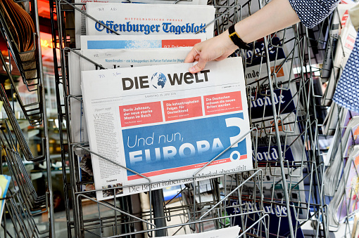 Strasbourg, France - June 25, 2016: Woman buying Die Welt newspaper with shocking headline titles at press kiosk about the Brexit referendum in United Kingdom requesting to quit the European Union