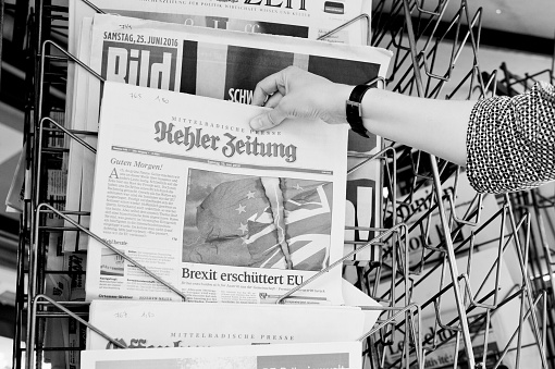 Strasbourg, France - June 25, 2016: Woman buying Kehler Zeitung newspaper with shocking headline titles at press kiosk about the Brexit referendum in United Kingdom requesting to quit the European Union