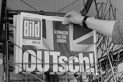 Strasbourg, France - June 25, 2016: Woman buying Bild Magazine newspaper with shocking headline titles at press kiosk about the Brexit requesting to quit the European Union