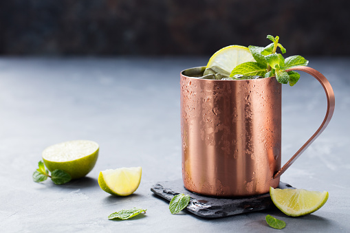 Cold Moscow Mules cocktail with ginger beer, vodka, lime Grey stone background. Copy space