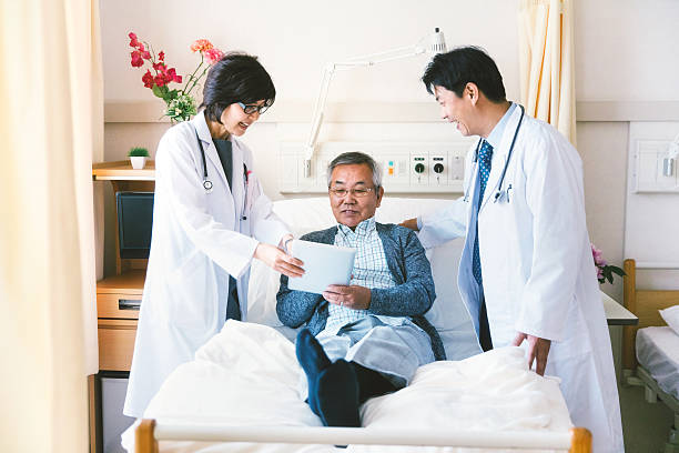 japanische arzt im gespräch mit einem patienten im krankenhaus - bed hospital prognosis patient stock-fotos und bilder