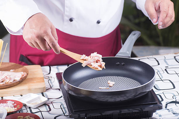 istock Chef putting bacon to the pan for fried 542701622