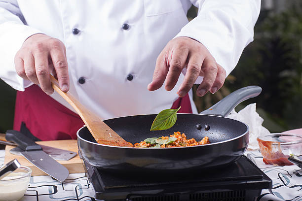 istock Chef putting basil to pan for cooking spaghetti chicken sauce 542701938