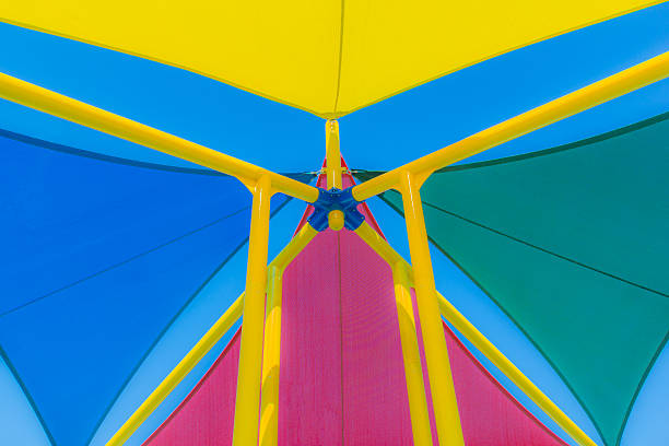 multi farbige sonnenschirmen gegen blauen himmel, nahaufnahme (p) - shade sail awning textile stock-fotos und bilder