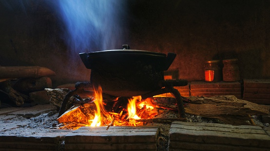 Rural image pot of food on burning wood fire.