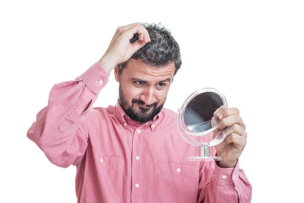 istock Man worried about gray hair looking in a mirror 542709826