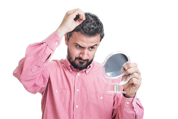 istock Man worried about gray hair looking in a mirror 542709924