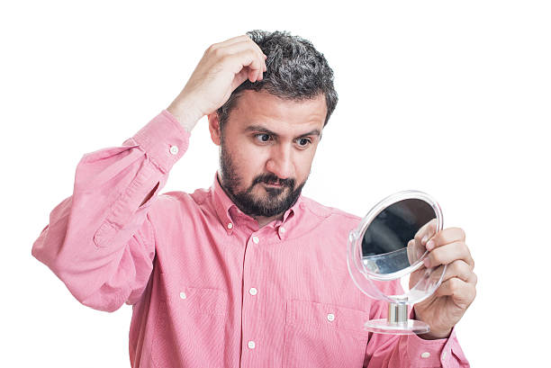 istock Man worried about gray hair looking in a mirror 542710552