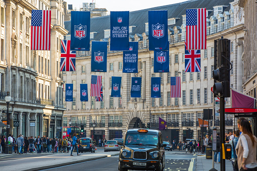 London, UK - October 4, 2015: Regent street decorated with flags and lots of walking people. Public transport on the road, taxis, cars and buses