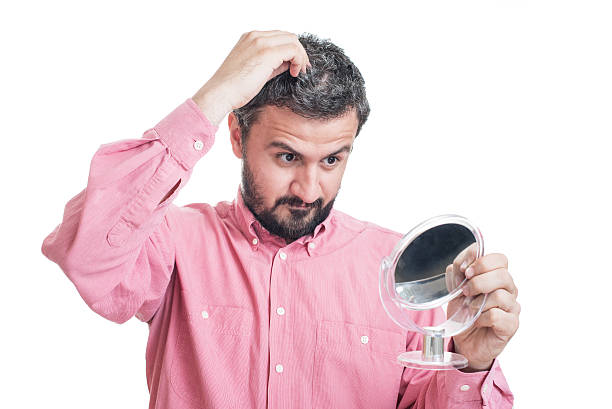 istock Man worried about gray hair looking in a mirror 542710626