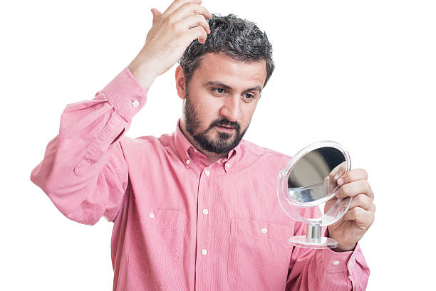 istock Man worried about gray hair looking in a mirror 542710690