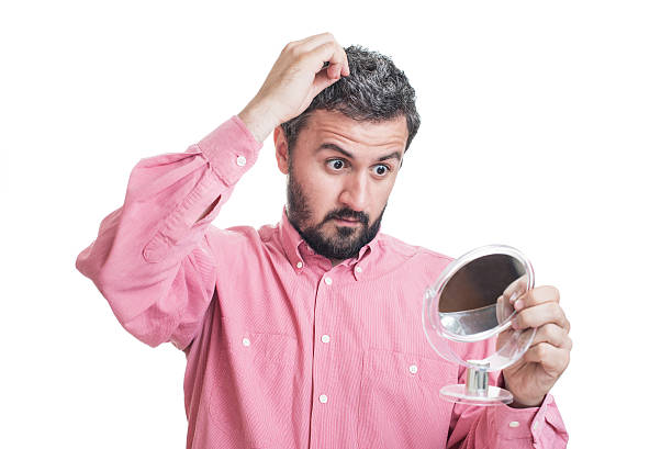 istock Man worried about gray hair looking in a mirror 542710762